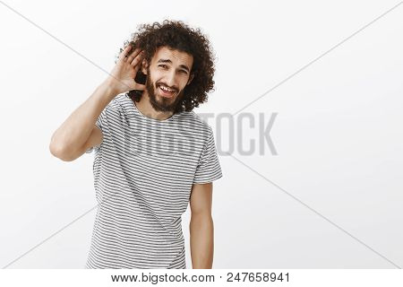 Studio Shot Of Carefree Good-looking Mature Guy With Beard And Afro Hairstyle, Holding Hand Near Ear
