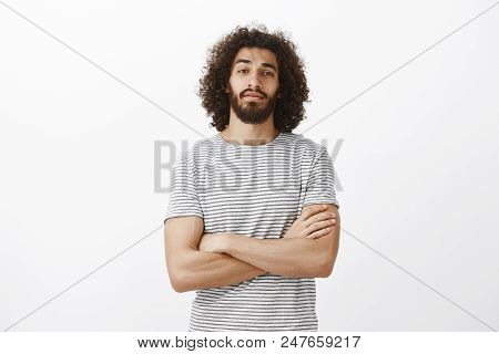Indoor Shot Of Popular Handsome Male Model With Beard And Afro Hairstyle, Holding Hands Crossed On C