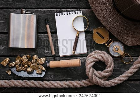 Blank Notepad Page, Hat, Flask, Shovel Full Of Gold Ore, Compass, Rope And Magnifying Glass On Aged 