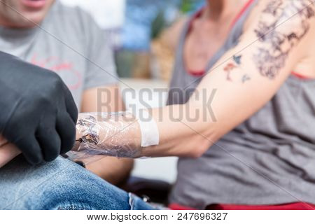 Close-up of the wrapped forearm of a young woman after getting a new cool tattoo in a modern studio with sterile safety supplies