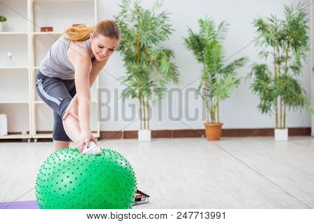 Young woman exercising with stability ball in gym