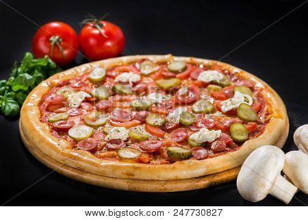 Delicious Tasty Pizza With Mozzarella, Sausages, Cucumber, Pepper And Sauce On Wooden Board On Dark 