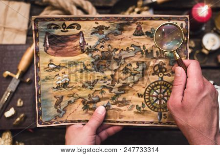 Treasure Map In Treasure Hunter Hands. Pirate Man Learning An Old Map With Red Mark.