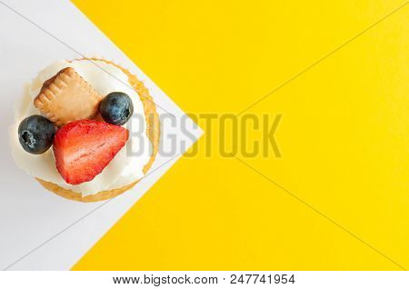 Cupcake With Cream, Strawberry, Blueberry And Cookie On Yellow White Background. Looks Like A Flag. 