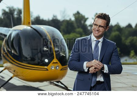 On Time. Cheerful Young Executive Smiling After Checking The Watch While Standing At A Helipad And W