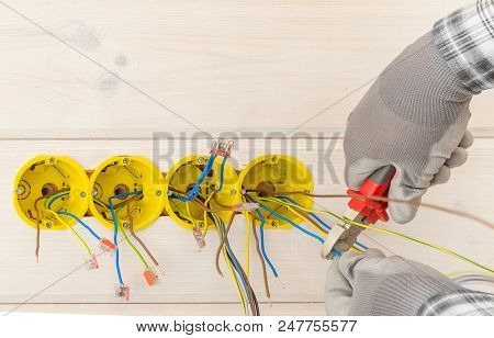 Hands Of Electrician Installing Electrical Socket With Screwdriver In The Wall In New Wooden House