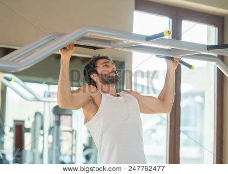 Man doing free body calisthenic pull-ups in a gym