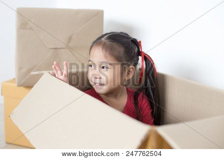 Asian Girl Playing In The Box At Home. Kid Sitting Inside Box With Attractive Smiling.
