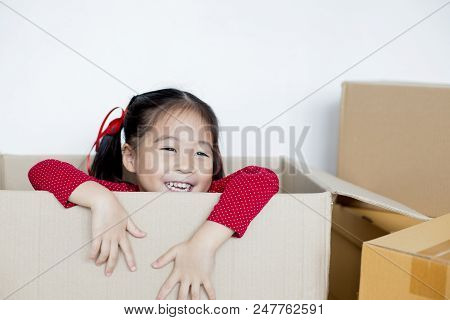 Asian Girl Playing In The Box At Home. Kid Sitting Inside Box With Attractive Smiling.