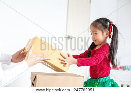 Attractive Asian Girl Try To Move A Box At Home. Kid Holding Box With Attractive Smiling. Kid With H