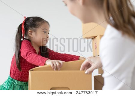 Attractive Asian Girl Try To Move A Box At Home. Kid Holding Box With Attractive Smiling. Kid With H