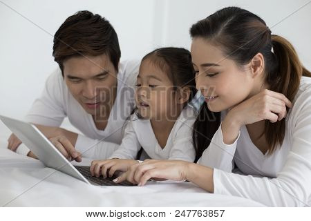 Attractive Little Girl Using Laptop With Mom And Dad Together. Girl Learning To Use Laptop. Happy Fa