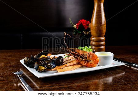 Delicious Seafood Dish. Fish Fillet, Mossels And Prawn Served With Appetizing Sauce In The White Pla