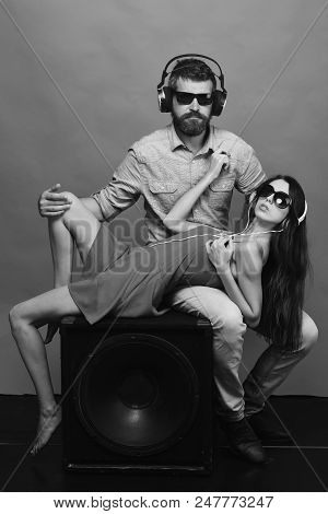 Couple In Love Lies On Loudspeaker On Green Background. Guy With Beard And Lady With Serious Faces E