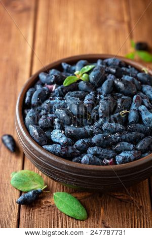 Honeysuckle Berries Or Lonicera Caerulea In Ceramic Bowl On Wooden Background