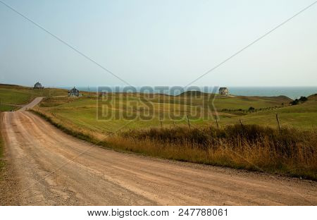 Dirt road to the sea with few coloured house in Magalen island in Quebec in Canada