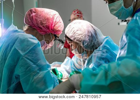 Surgeons Team Working With Patient In Surgical Operating Room. Breast Augmentation