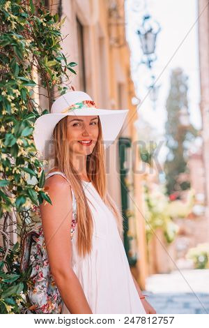 Beautiful Girl In A Shite Dress And Summer Hat Exploring The Old Town Of Taormina On Sicily Island.