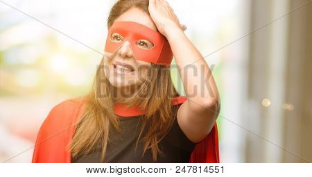 Middle age super hero woman wearing red mask and cape terrified and nervous expressing anxiety and panic gesture, overwhelmed