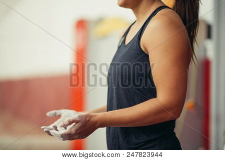 Unrecognizable Sporty Female In Black Vest Showing Chalked Hands Standing At Indoor Climbing Gym Wal