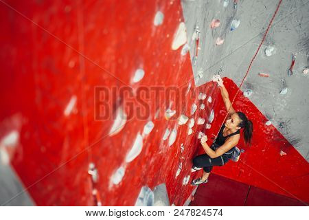 High Angle View Of Sporty Brown-haired Woman Exercising Wall Climbing On Colorful Red Artificial Roc