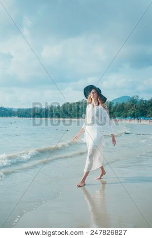 Handsome Girl In Hat On The Beach Background. Portrait Of A Woman In White Clothes And Balck Hat On 