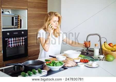 Smiling Caucasian Woman Making Healthy Meal And Chatting On Phone In The Domestic Kitchen.