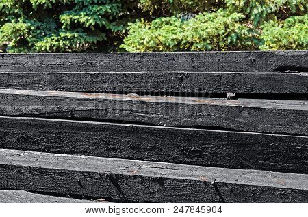 Set Of New Creosote Impregnated Wooden Sleepers Are Stacked On Each Other Against The Background Of 