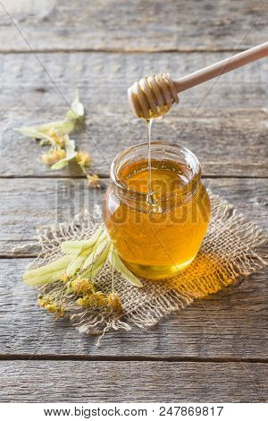 Glass Jar Of Honey, Linden Flowers On Wooden Background