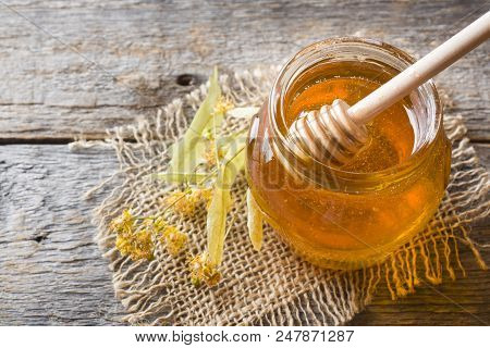 Glass Jar Of Honey, Linden Flowers On Wooden Background