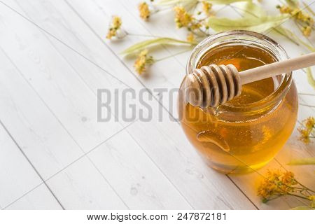 Glass Jar Of Honey, Linden Flowers On Light Background. Copy Space