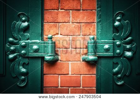 Symmetrical ornate metal hinges with red brick wall and vignette. Traditional style door detail in Berlin, Germany. Space for your text. 