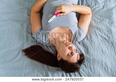 Sad Woman On Bed With Negative Pregnancy Test