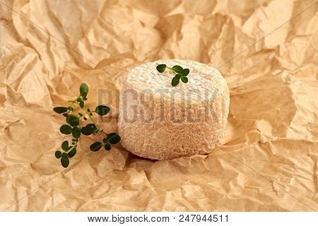 Crottin Cheese With Thyme Leaves On Brown Package Paper.