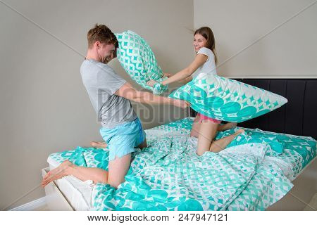 Young Couple Having Fun In Bedroom With Pillow Fight.