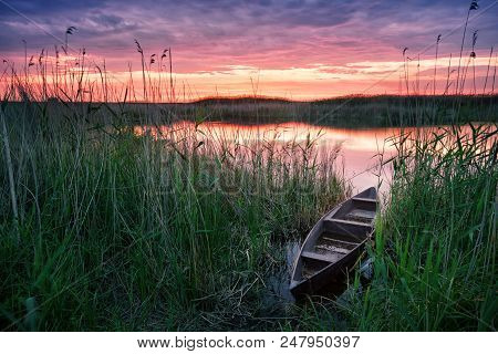 Wooden Boat On The Lake At Sunset. Summer Landscape. A Wooden Boat Stands In Green Reeds On The Bank