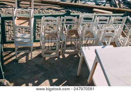 A Lot Of White Chairs Stacked On Top Of Each Other At Sunset Stand On The Embankment Near The Sea