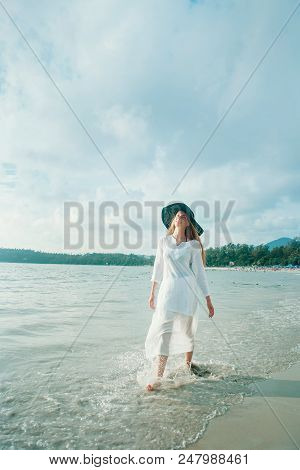 Handsome Girl In Hat On The Beach Background. Portrait Of A Woman In White Clothes And Balck Hat On 