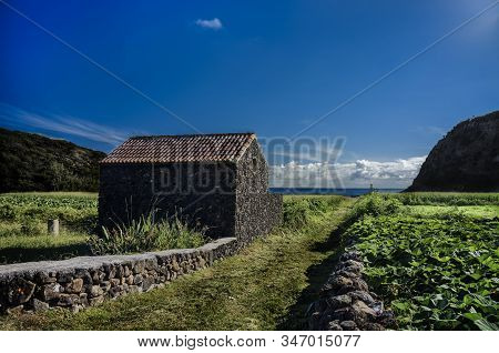 View Of The An Black Stone Hosue In A Green Landscape. Terceira, Azores, Portugal.