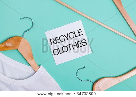 White T-shirts On Wooden Hangers Lying On Ponk Background, Top View