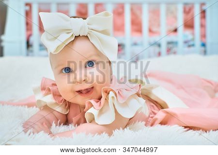 A Little Girl With A Bow On Her Head Is Lying On The Bed
