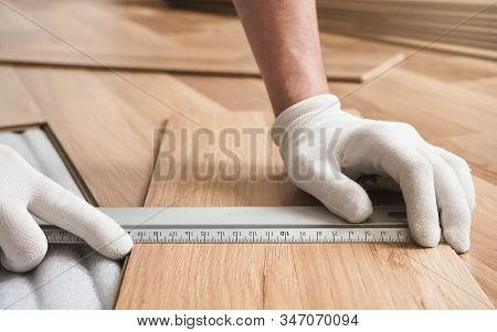 Installing Laminated Floor, Detail On Man Hands Holding Metal Ruler Over Wooden Tile, White Foam Bas