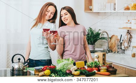 Women Home Party. Cooking Leisure Hobby. Two Ladies Preparing Food Drinking Wine In Kitchen.