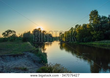 Sunset Over The Meandering River, Which Is Hidden Behind The Crown Of Trees Growing On The Banks. Ph