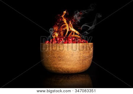 Peruvian Pink Pepper With Burning Fire In Bowl Isolated On Black Glass