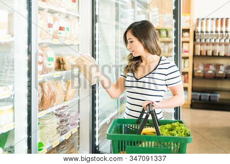 Beautiful Woman Reading Label On Bread While Shopping In Grocery Store