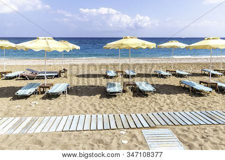 Empty Sunbeds And Umbrella On Afandou Beach Near Faliraki (rhodes, Greece)
