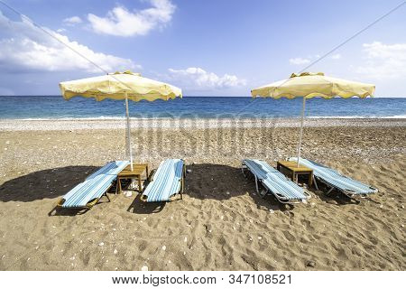 Empty Sunbeds And Umbrella On Afandou Beach Near Faliraki (rhodes, Greece)