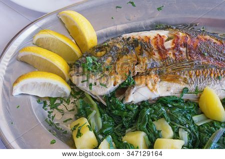Balkan Cuisine. Grilled Fish ( Sea Bream ) With Green Leafy Vegetables And Slices Of Lemon
