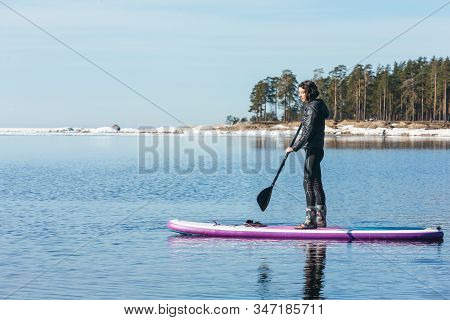 Attractive Caucasian Woman In Black Wetsuit Paddle On Sup Board With An Oar. Female Floating On Stan